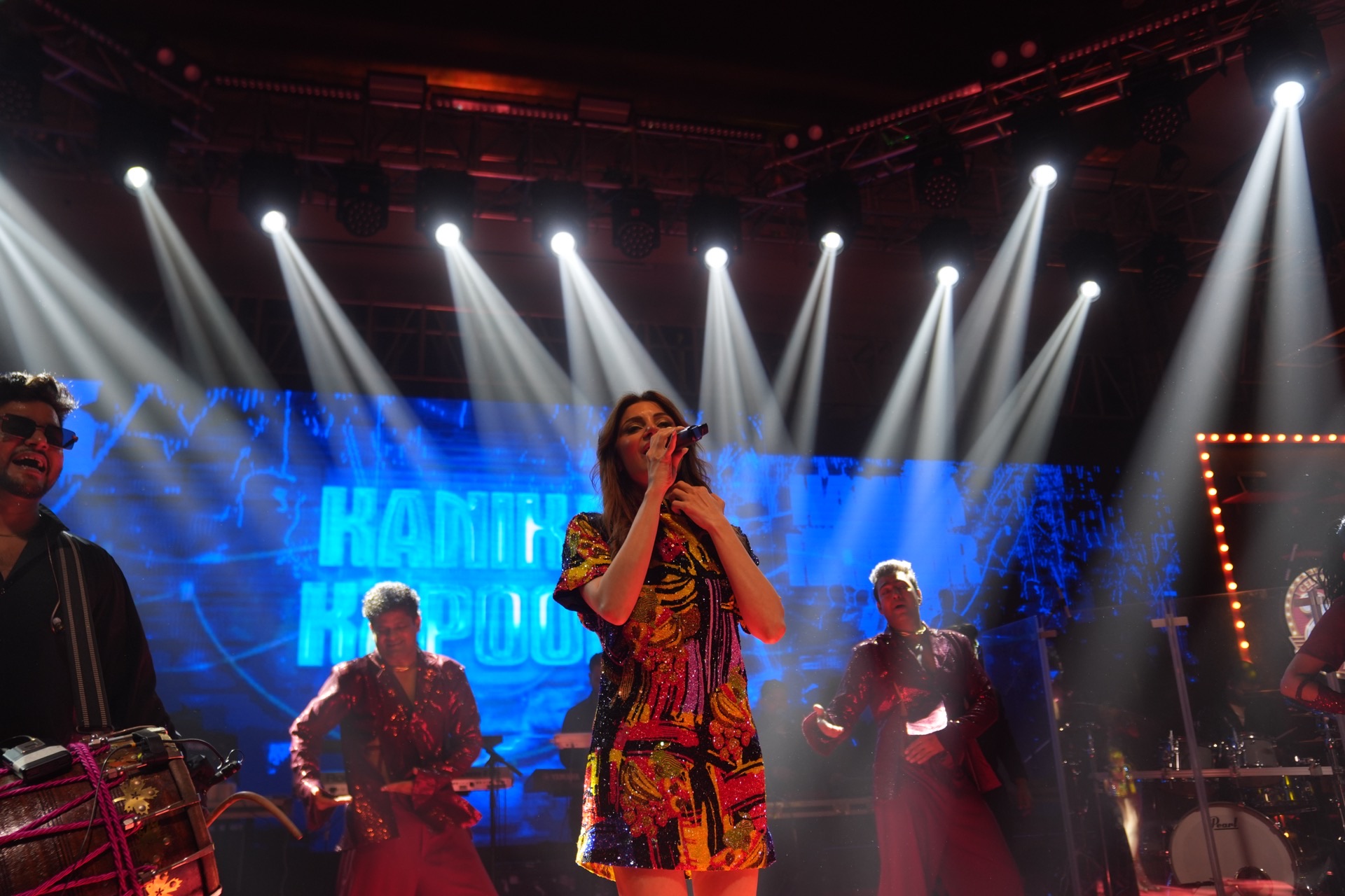 Singer on a concert stage under white beams, shot for social media.