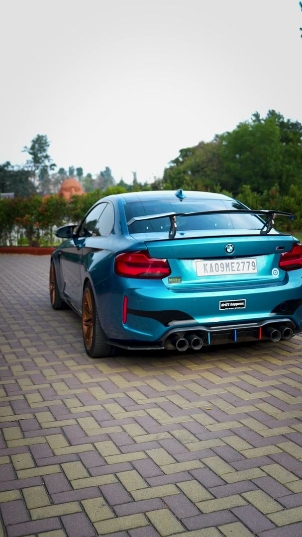 Teal BMW M2 from behind with a large rear wing.