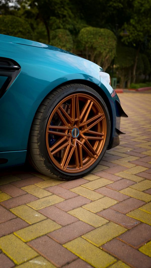 Bronze multi-spoke wheel of the teal BMW M2.
