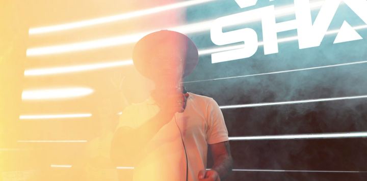 Performer silhouetted by a bright flare of stage light.