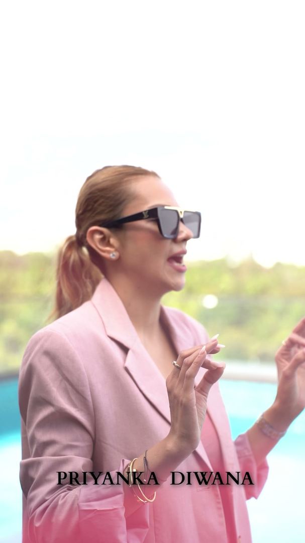 Grooming mentor in a pink blazer and dark sunglasses by the pool.