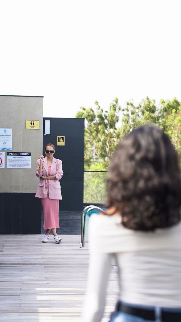 Mentor watches a contestant walk across the rooftop deck.