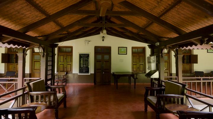 Timber-roofed hall with rows of wooden chairs.