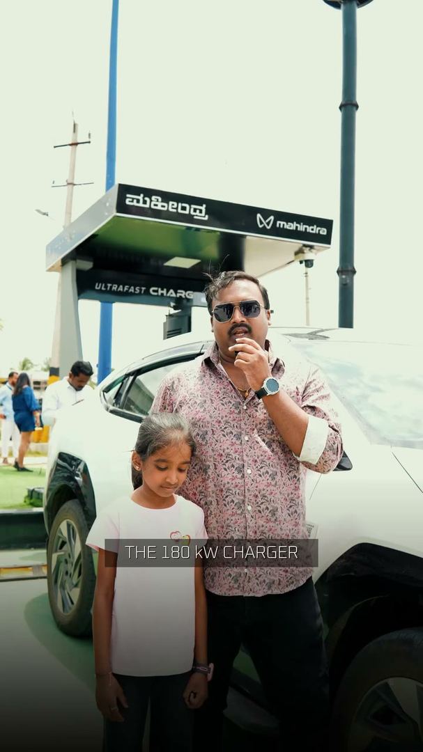 Father and daughter stand by their SUV at a fast charger.