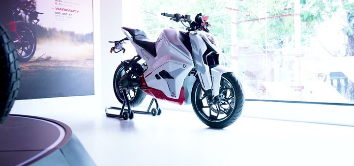 White and red Ultraviolette motorcycle on a stand in soft daylight.