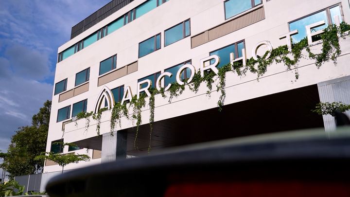 Arcor Hotel facade with hanging green plants, seen from below.