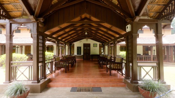 Long timber verandah with wooden chairs and a red floor.