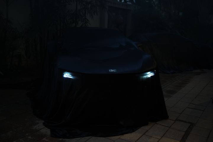 Headlights glow through a black cover in a dark garden.