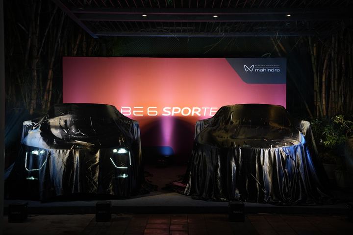 Covered cars lit in pink and red before the evening reveal.