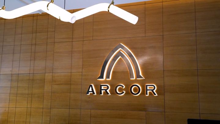 Backlit Arcor logo on a warm wooden wall.