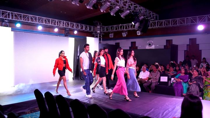 Finalists walk the runway together under purple stage light.