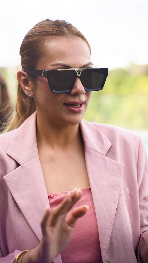 Grooming mentor in sunglasses talks to contestants on the pool deck.
