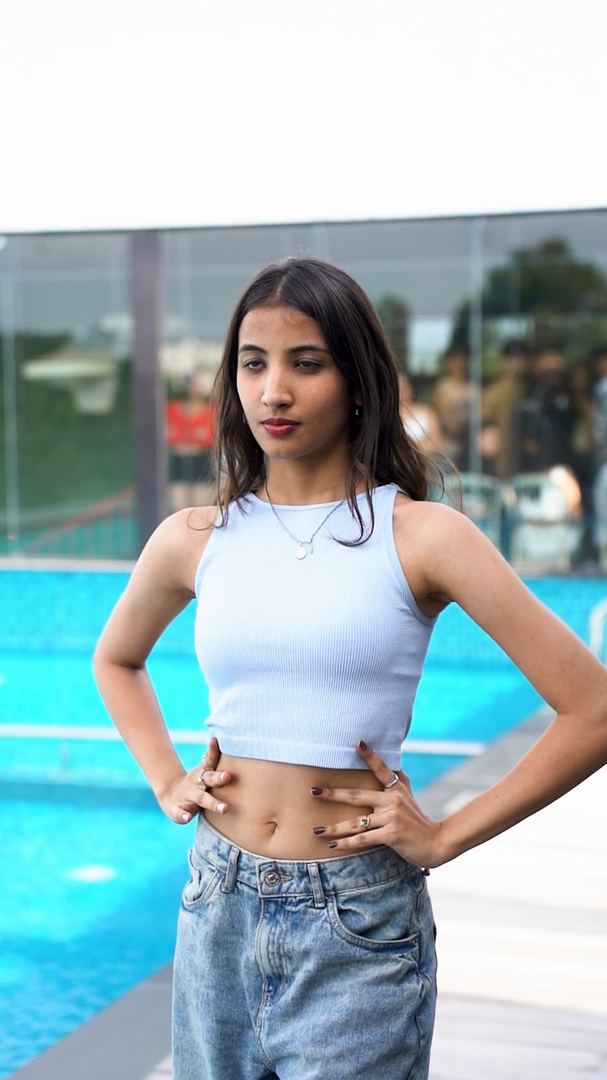 Contestant poses with hands on hips beside the rooftop pool.