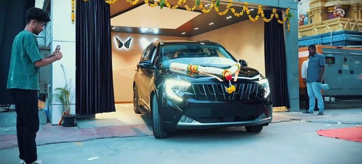 Garlanded black SUV rolls out through a curtained doorway.