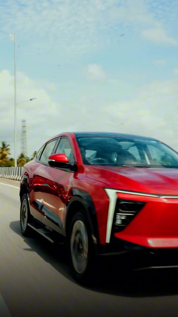 Red electric SUV driving on an open highway.