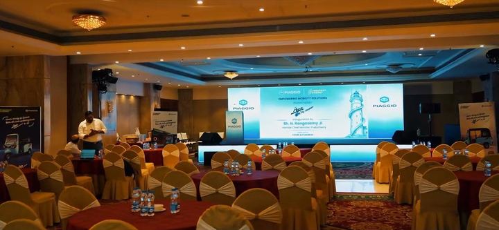Hotel ballroom set up for the Piaggio launch, screens lit blue.