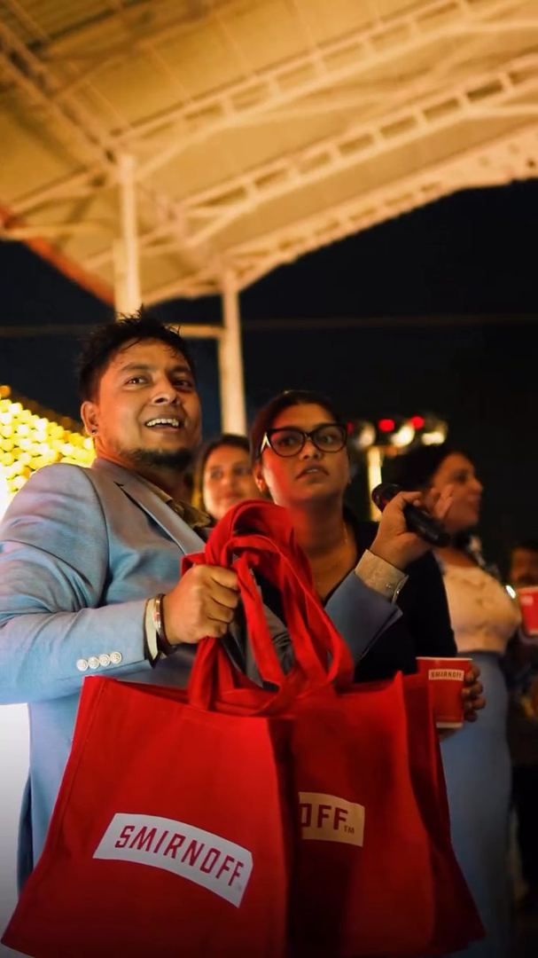 Guests hold up red Smirnoff gift bags.