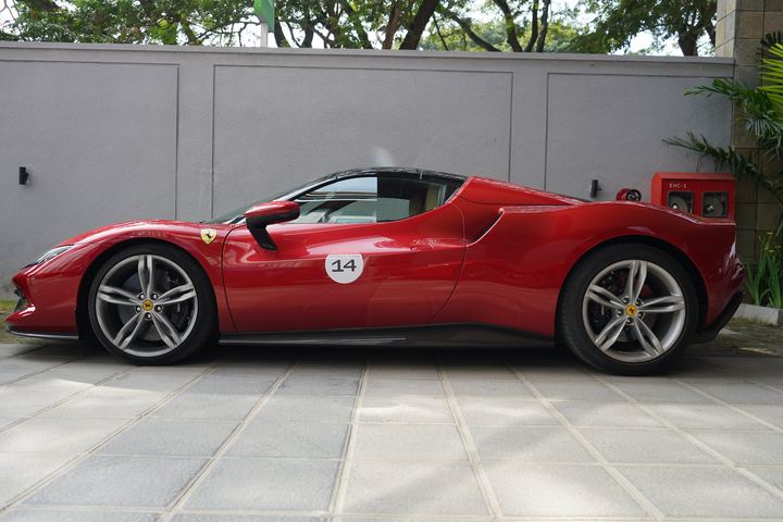 Red Ferrari with race number 14 in side profile against a grey wall.