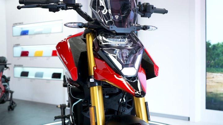 Red Ultraviolette motorcycle headlamp and gold forks in a white showroom.