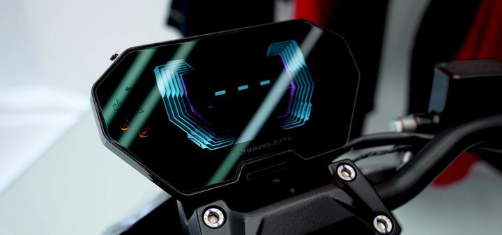 Digital instrument display of an Ultraviolette motorcycle glowing in the dark.